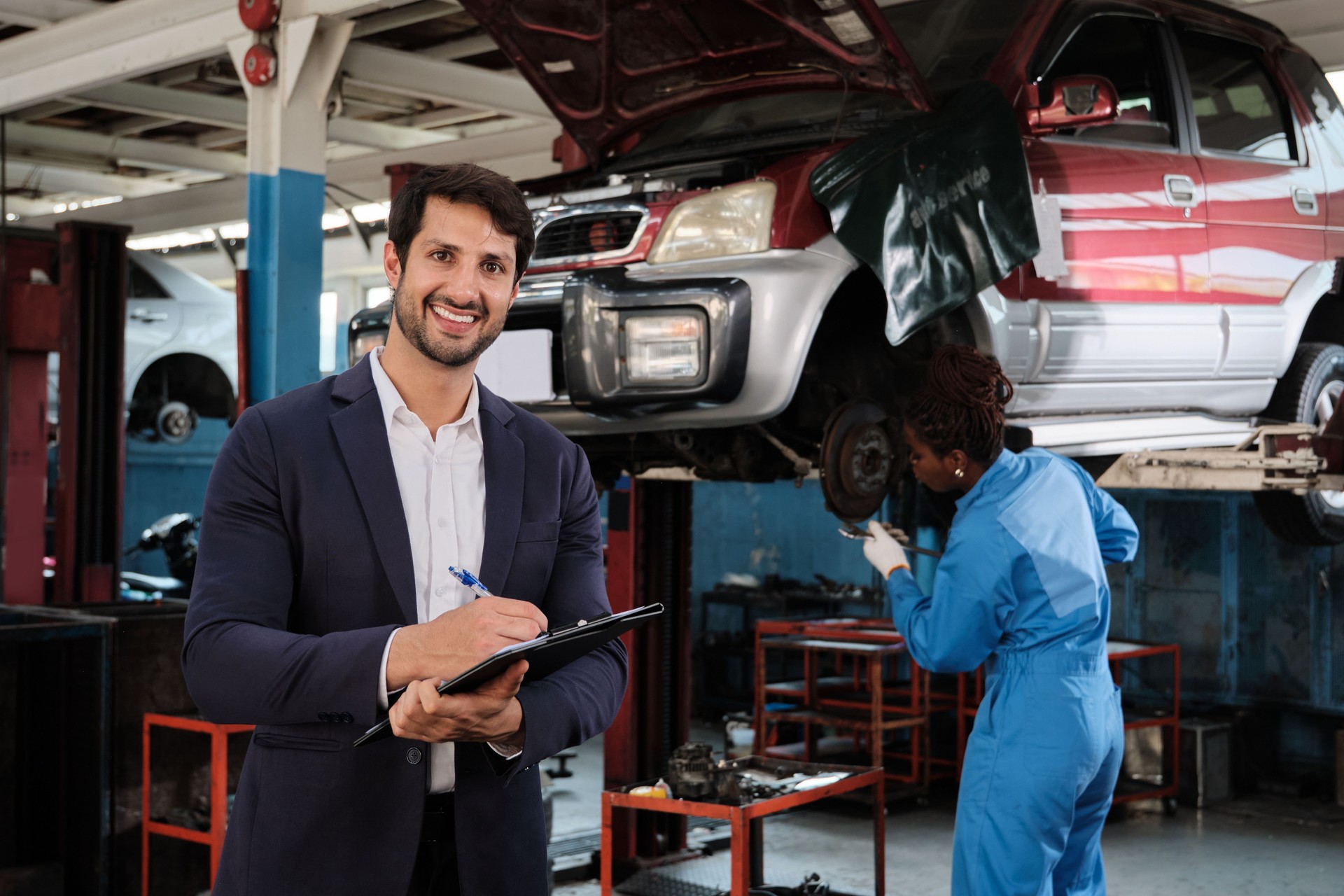 Latino male mechanic manager with documents and cheerful smiles.